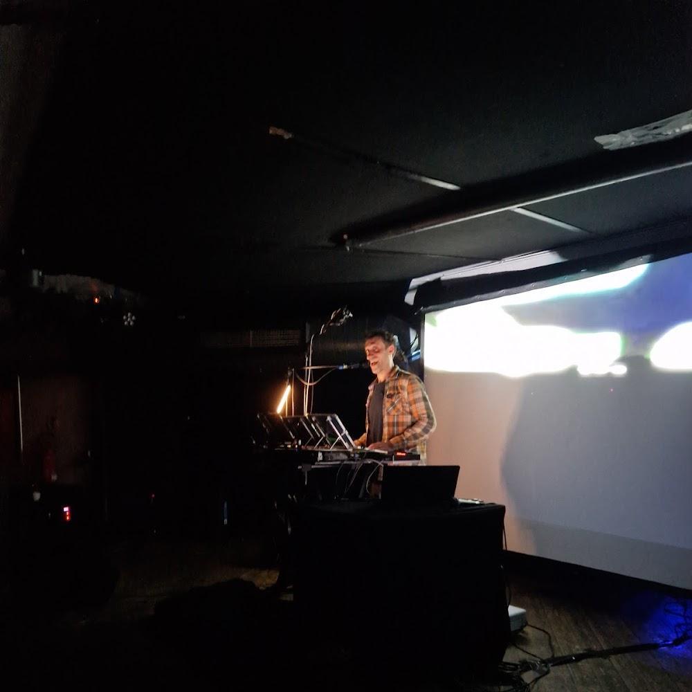 Man performing on stage with a projector screen.